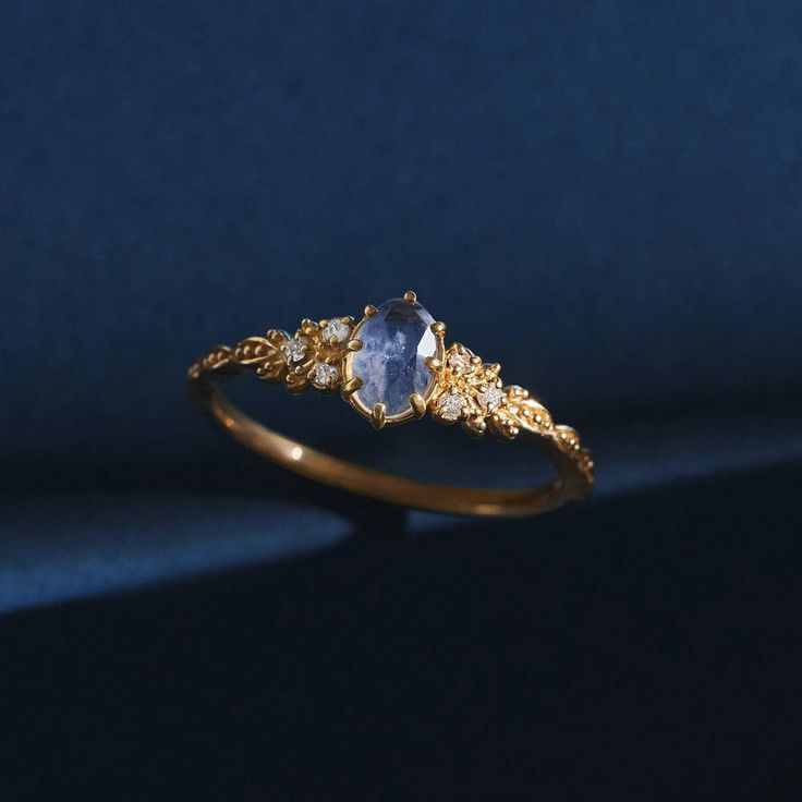 a gold ring with an oval blue stone surrounded by small white diamonds