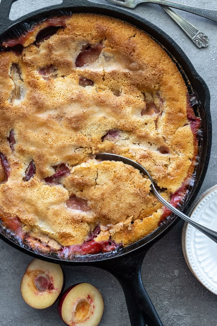 a skillet with some fruit in it next to two slices of apples and a fork