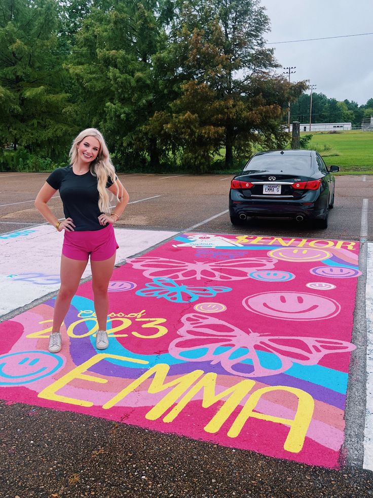 a woman standing in front of a parking lot with a pink rug on the ground