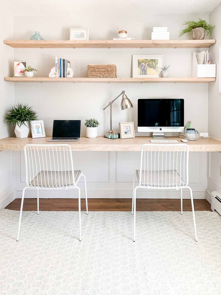 two white chairs sitting in front of a desk with a computer on top of it