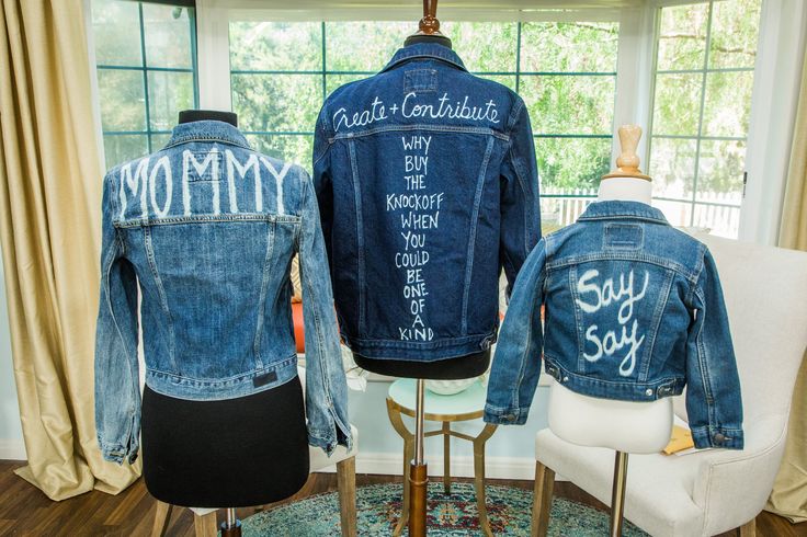 two denim jackets with writing on them are sitting on mannequins in front of a window