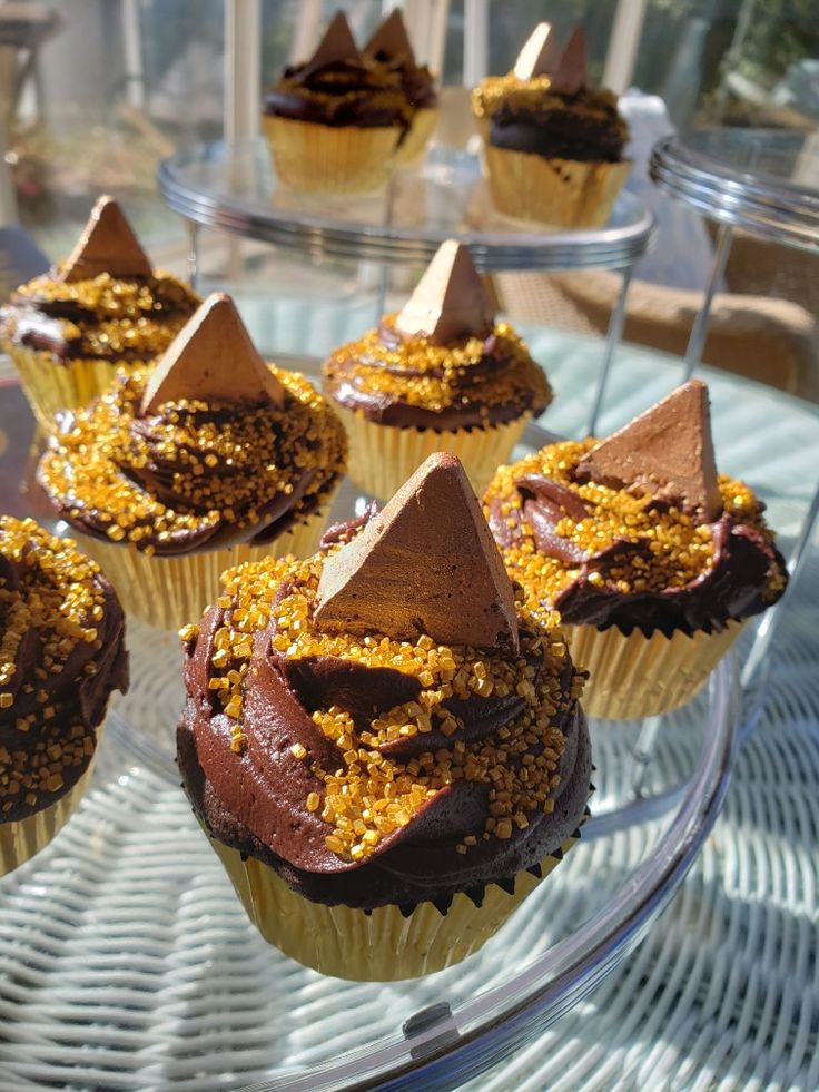 cupcakes with chocolate frosting and gold sprinkles on a glass platter