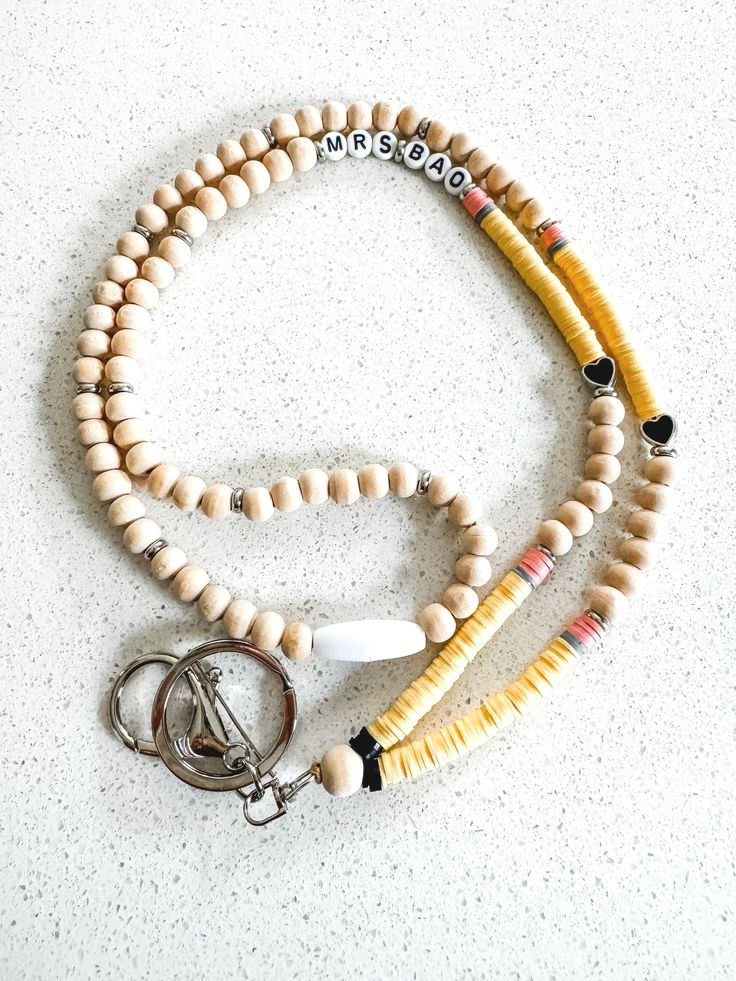 Each bead is meticulously chosen to replicate the iconic yellow, pink, and silver hues of a classic pencil, capturing the essence of a tool that is synonymous with learning and creativity. The lanyard is both stylish and functional, providing a convenient way for teachers to carry their ID badges, keys, or small essentials. It serves as a daily reminder of their pivotal role in shaping young minds and fostering a love for knowledge. Whether worn in the classroom or at educational events, this pe Heishi Bead Lanyard, Diy Teacher Lanyard, Beaded Lanyard, Diy Lanyard, Work Badge, Teachers Diy, Teacher Lanyard, Acrylic Letters, Beaded Lanyards