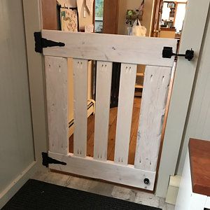 a white wooden gate with black latches on the front door and side walk way