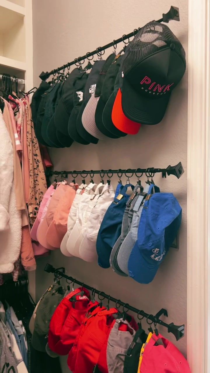 there are many hats and shorts hanging on the rack in this closet, but no one is wearing them