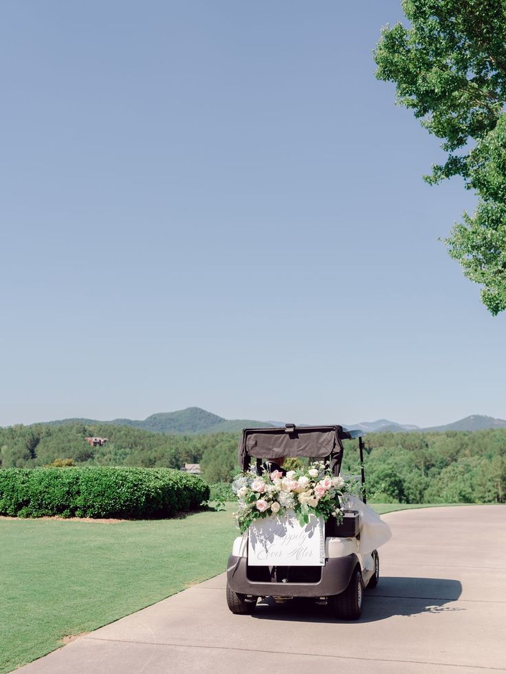 a golf cart decorated with flowers and greenery is parked on the side of the road