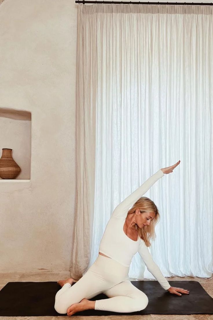 a woman is doing yoga in front of a window