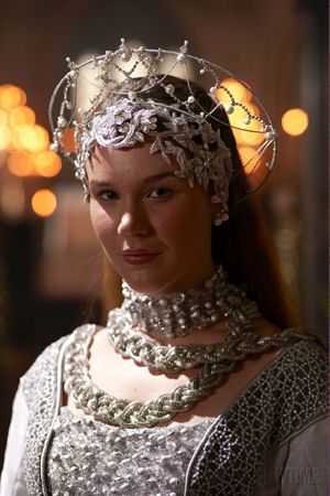 a woman with long hair wearing a tiara and pearls on her head is looking at the camera