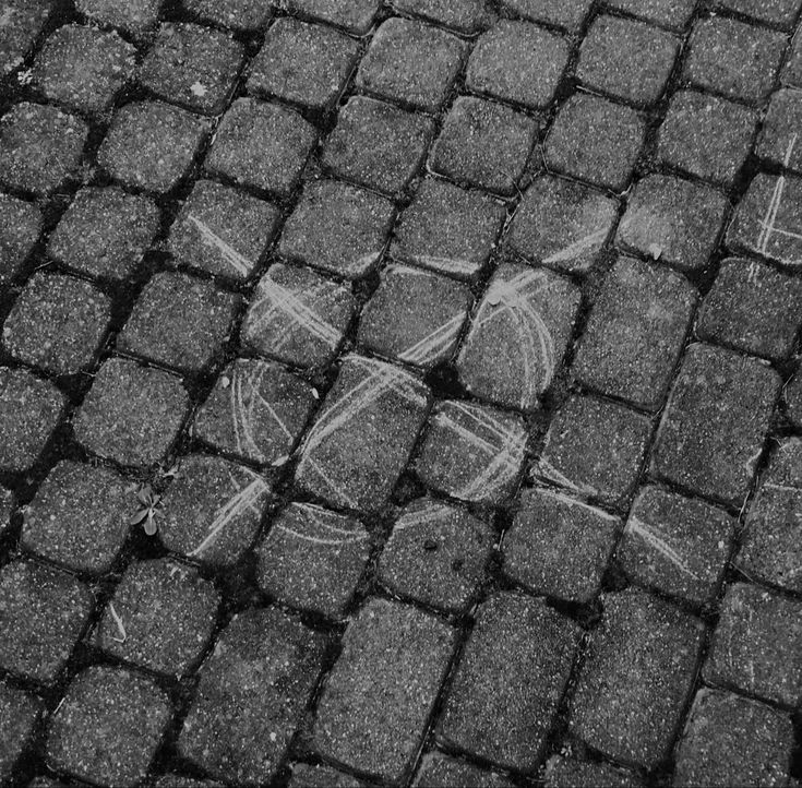 the word love is written in chalk on cobblestone pavement with two arrows pointing to each other