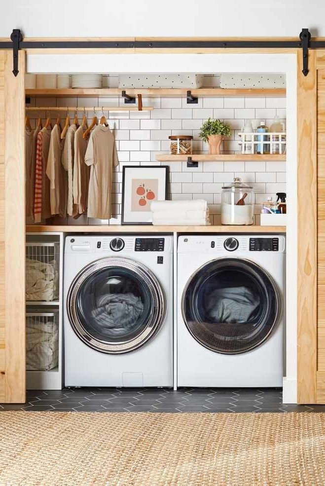 a washer and dryer sitting in front of a shelf with clothes on it