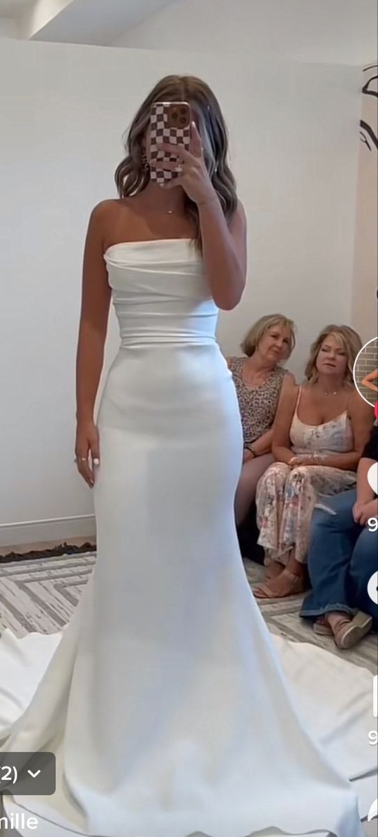 a woman in a white wedding dress is taking a selfie with her cell phone