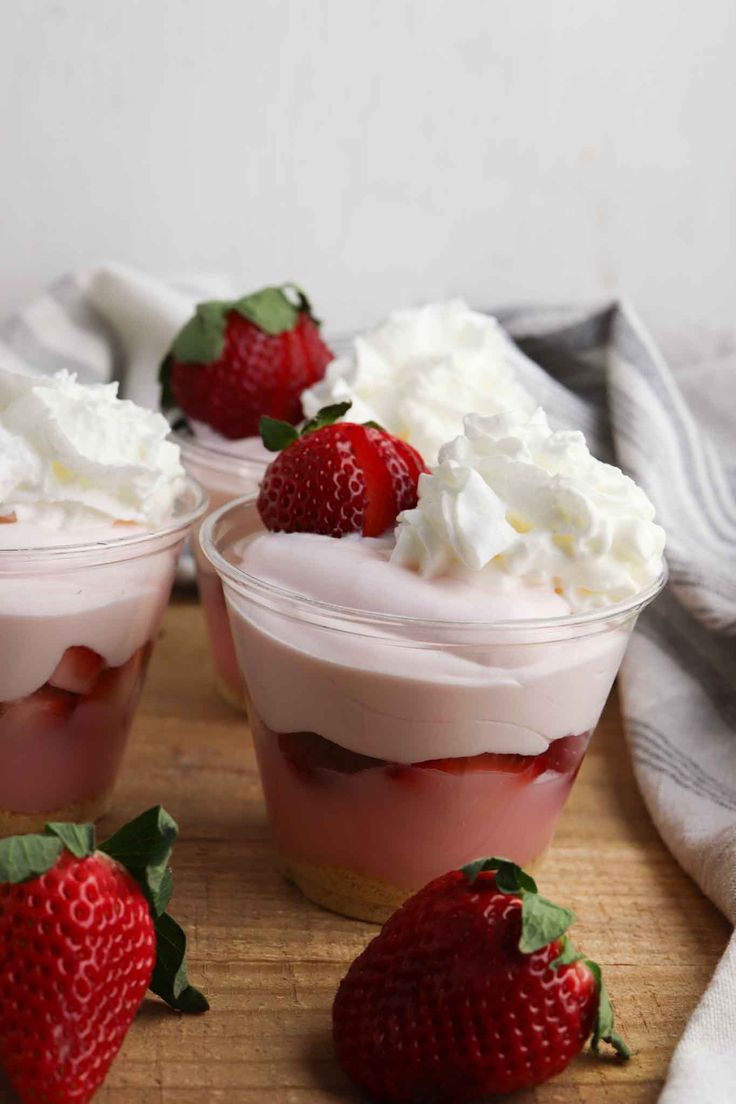 three dessert cups with whipped cream and strawberries