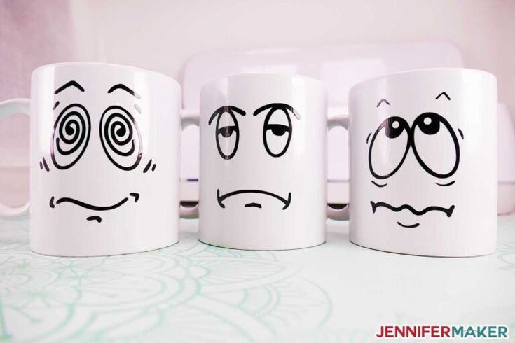 three coffee mugs with faces drawn on them, one has eyes and the other is frowning