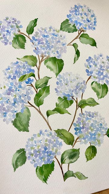 watercolor painting of blue flowers and green leaves on white paper with wood flooring