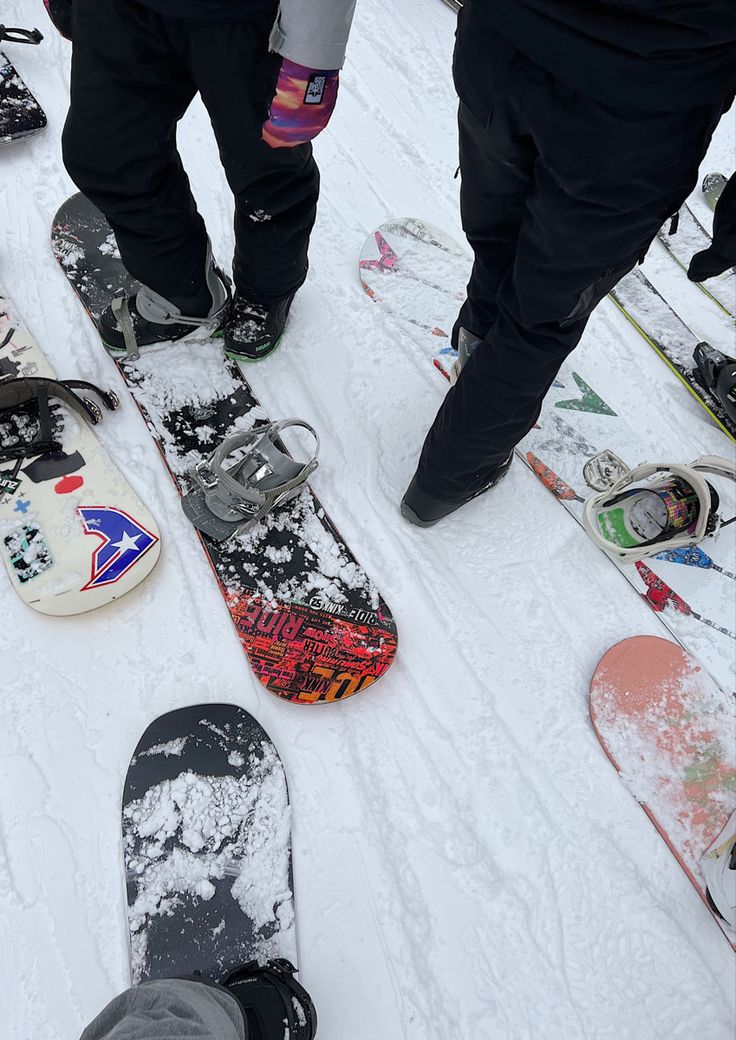 several snowboarders are standing in the snow with their feet propped up on them