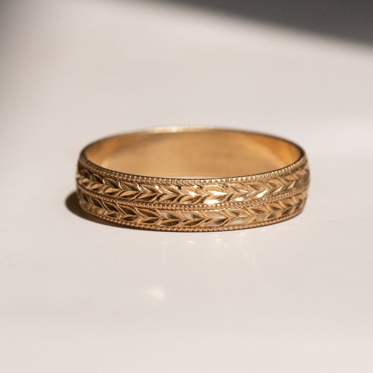 a gold wedding ring sitting on top of a white table