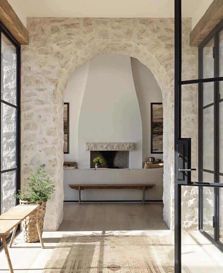 an arched doorway leads into a living room with stone walls and floor to ceiling windows