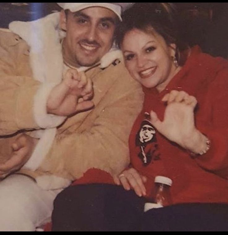 a man and woman sitting next to each other in front of a christmas tree with santa clause on it