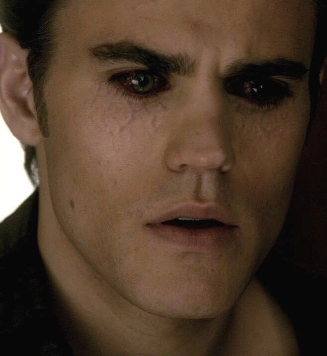 a close up of a person with blood on his face and eyeliners, looking at the camera