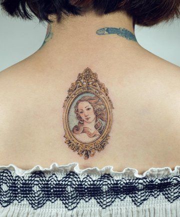 the back of a woman's shoulder with a portrait in a frame on it