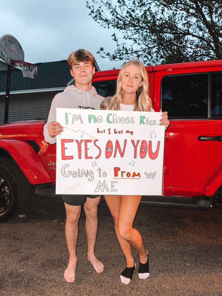 a man and woman holding a sign in front of a red truck