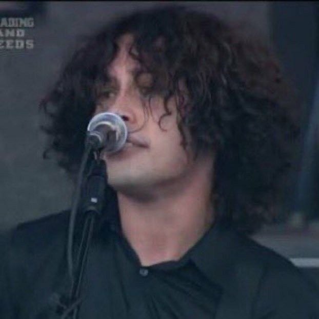 a man with curly hair singing into a microphone