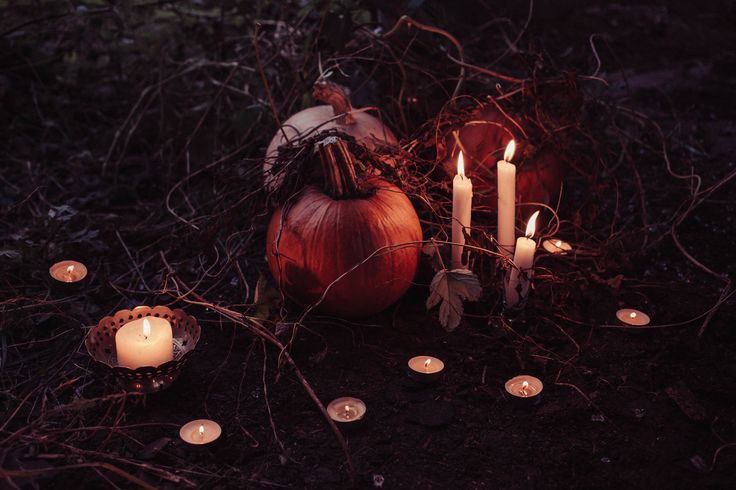 candles and pumpkins are arranged on the ground