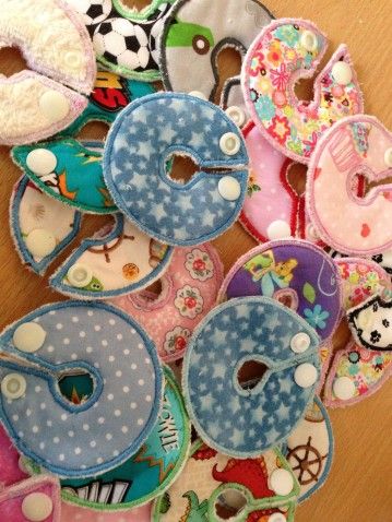 a pile of baby bibs sitting on top of a wooden table