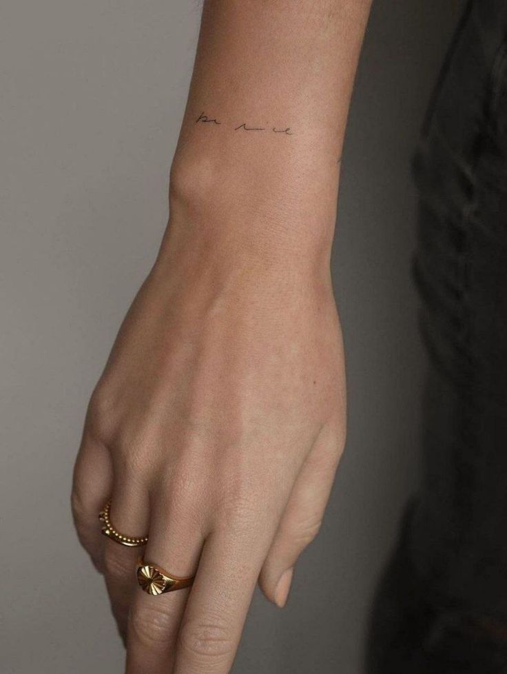 a person with a small tattoo on their left wrist and the word love is written in cursive writing