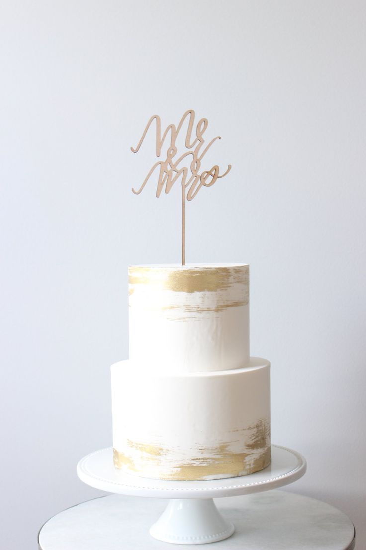 a white cake topped with a wooden mr and mrs topper