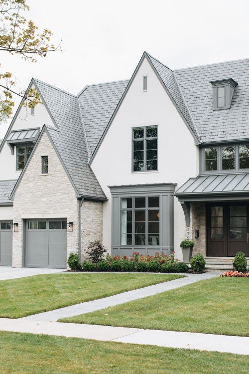 a large white house with two garages and lots of grass in front of it