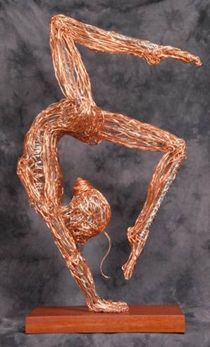 a sculpture made out of copper wire on top of a wooden base with a person doing a handstand