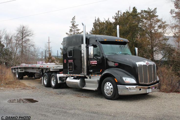 a large semi truck parked on the side of a road next to trees and bushes