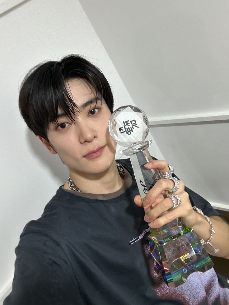 a young man holding up an award in his right hand and looking at the camera