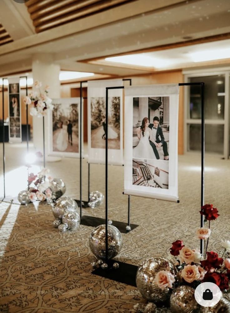 an aisle with pictures and flowers on the floor in front of them at a wedding