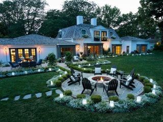 an outdoor patio and fire pit in front of a large house