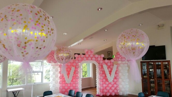 balloons and streamers decorate the entrance to a room decorated with pink, gold and white decorations