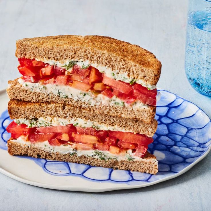 two halves of a sandwich on a blue and white plate with water in the background