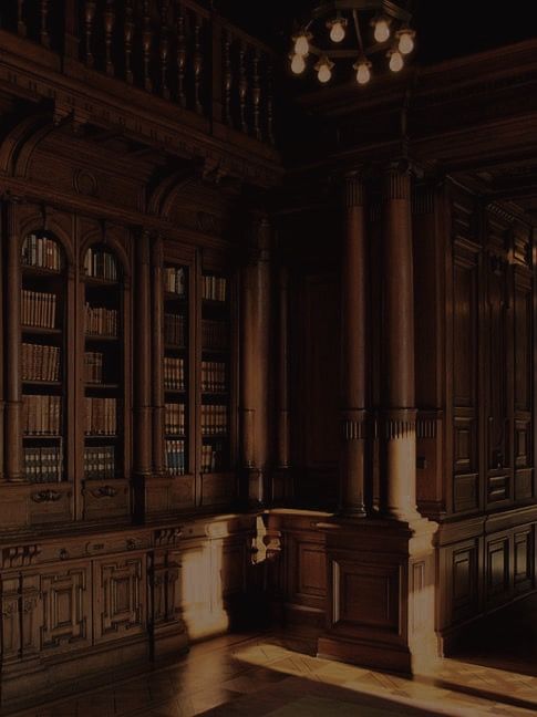 an empty room with wooden bookshelves and chandelier in the center,