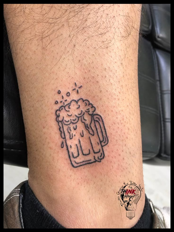 a tattoo on the leg of a man with a beer mug and bubbles coming out of it