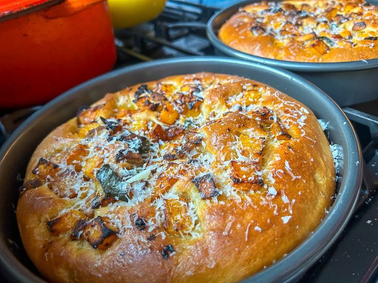 two breads sitting on top of an oven with cheese and other toppings in them