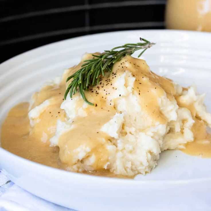 mashed potatoes covered in gravy and garnished with a sprig of rosemary