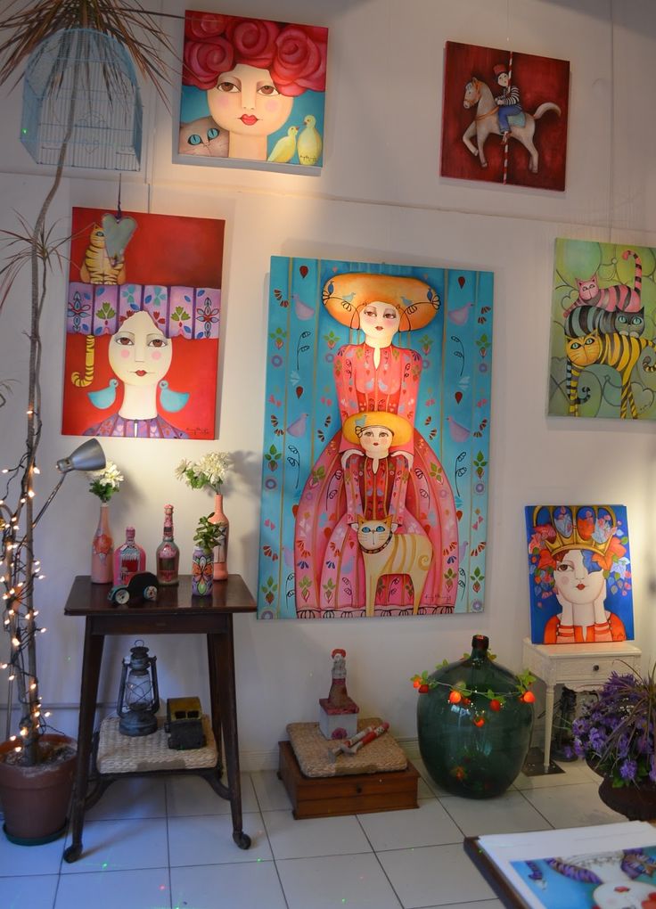 several paintings hang on the wall next to a table and potted plant in front of it