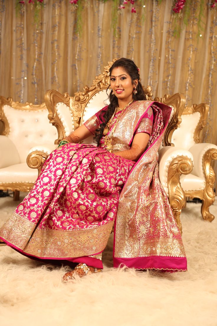 a woman in a pink and gold sari sitting on a couch