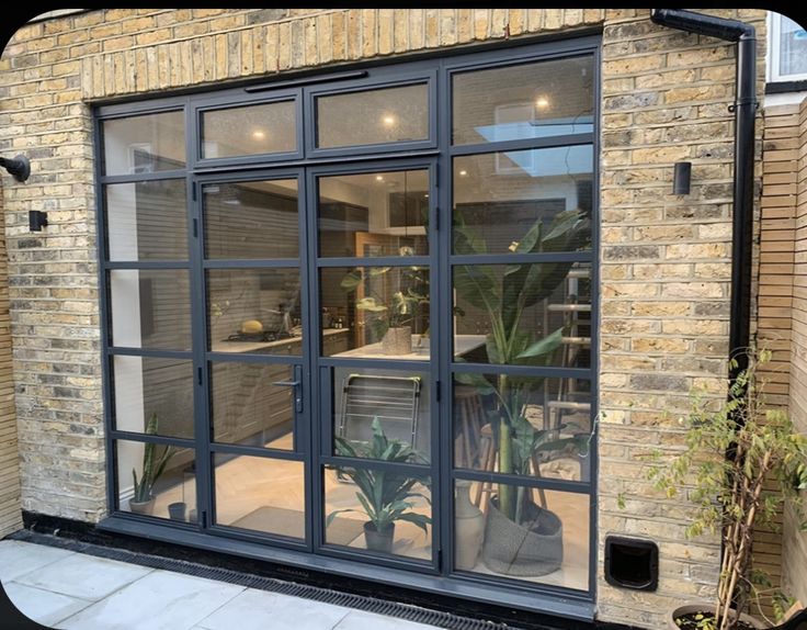 a brick building with glass windows and plants