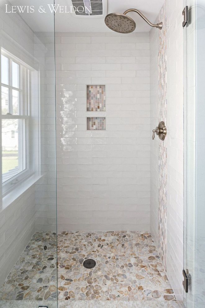 a walk in shower sitting under a window next to a sink and bathtub covered in pebbles