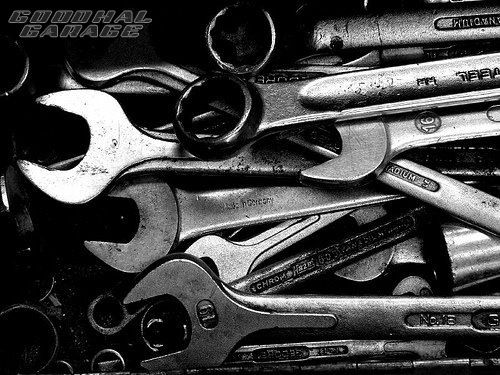 black and white photograph of various wrenches in a bin with the word repair written on it