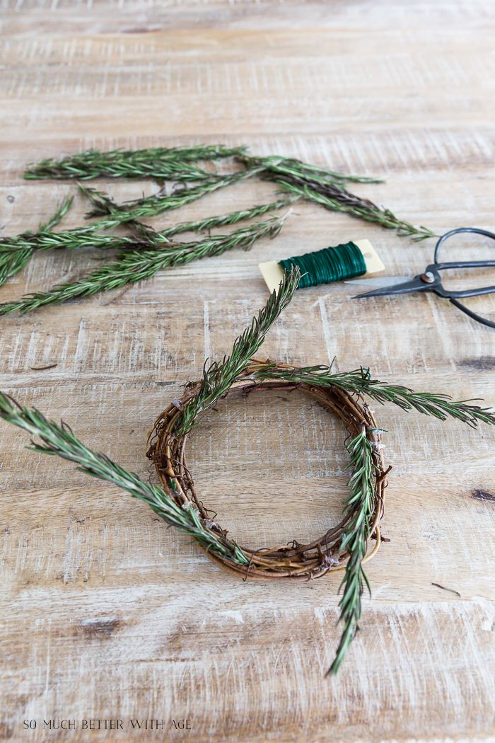 a pair of scissors sitting on top of a wooden table next to some green twigs