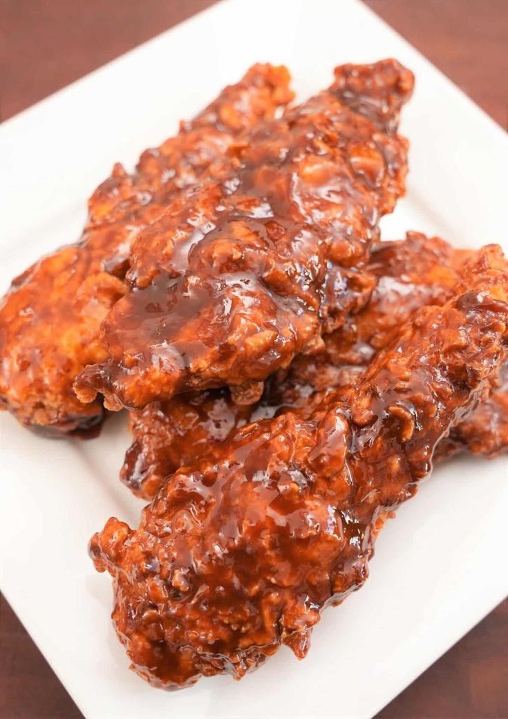 two pieces of meat covered in gravy on a white plate