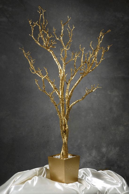 a small gold tree in a vase on a white cloth